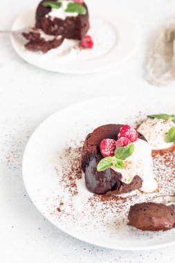 Lezzetli çikolata ya da kremalı lav keki, ahududu ve nane, açık gri beton arka plan. Sıvı merkezli sıcak çikolata tatlısı. Çikolatalı fondant.. 