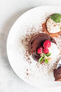 Lezzetli çikolata ya da kremalı lav keki, ahududu ve nane, açık gri beton arka plan. Sıvı merkezli sıcak çikolata tatlısı. Fondant au çikolata. Üst görünüm.