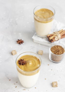 Uzun bardakta, baharatlı buzlu Dalgona kahvesi. Tüylü, kremalı, modaya uygun bir kahve. Kore kahvesi. Açık gri beton arkaplan. 