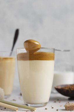 Lezzetli taze buzlu kahve, Dalgona kahvesi. Açık gri masada bardakta hazır kahve ile Kore içkisi. 