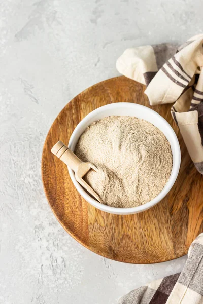 Buckwheat flour and a small wooden scoop with flour in a bowl, light grey concrete background. Gluten free flour, healthy nutrition.