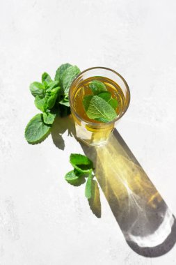 Sabah ışığında uzun bir bardak sıcak moorish nane çayı, güneş ışığı gölgesi. Sanatsal gölgeleri olan moda tarzı.