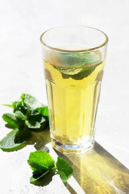 Sabah ışığında uzun bir bardak sıcak moorish nane çayı, güneş ışığı gölgesi. Sanatsal gölgeleri olan moda tarzı.