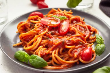 Baharatlı domates soslu, kiraz domatesli ve fesleğenli makarna. İtalyan mutfağı. Kapat..