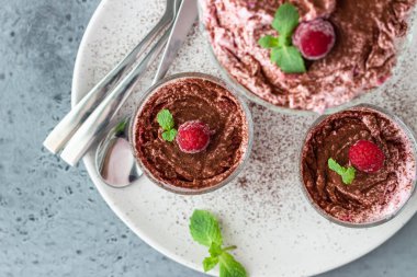 Pembe katmanlı tatlı, tiramisu ya da ahududu aromalı parfe ve bardakta kakao tozuyla süslenmiş nane şekeri. Yaz tatlısını pişirmek yok. Gri beton arkaplan. 