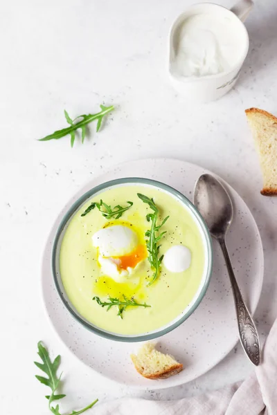 Potato cauliflower soup puree garnish with poached egg, olive oil and arugula served with artisan bread. Vegetarian healthy food concept. Light grey background. Top view. — Stock Image Potato Cauliflower Soup Puree Garnish Poached Egg Olive Oil Arugula Stock Image