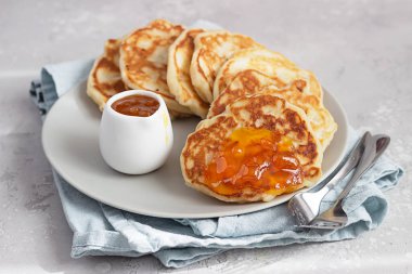 Amerikan gözlemeleri ya da seramik tabakta turuncu reçelli börekler. Açık gri taş arkaplan. 