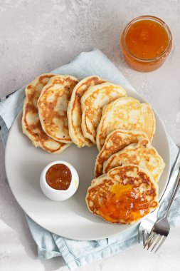 Amerikan gözlemeleri ya da portakal reçelli börekler seramik tabakta ve sütle birlikte şişe. Açık gri taş arka plan. Çocuklar için kahvaltı.. 