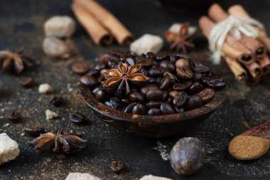 Aromatik kahve çekirdekleri, anason yıldızları, tarçın çubukları, esmer şeker küpleri ve koyu kahverengi beton arka planda hindistan cevizi. Noel pastası ve içecekleri için baharatlar..