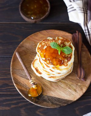 Bir yığın Amerikan gözlemesi ya da ahşap tabakta kayısı reçeli, koyu kahverengi beton arka plan. Kırsal tarzda. Seçici odak. 