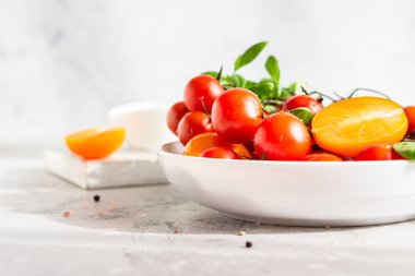 Beyaz tabakta bebek ıspanağı olan kırmızı kiraz ve sarı domatesler. Sağlıklı gıda, vegan ya da diyet konsepti.