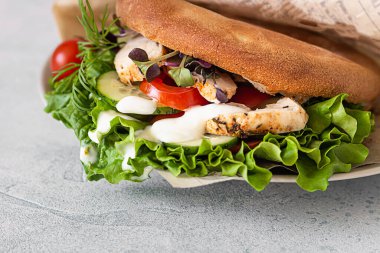 Taze sebzeli Pita ekmekli sandviç ve kızarmış tavuk. Açık gri taş arka plan. Paket yemek, sokak yemeği..