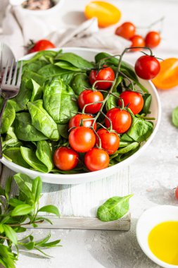 Beyaz seramik tabakta bebek ıspanak, kırmızı kiraz ve sarı domates. Taze sebzeler. Yaz hasat konsepti.