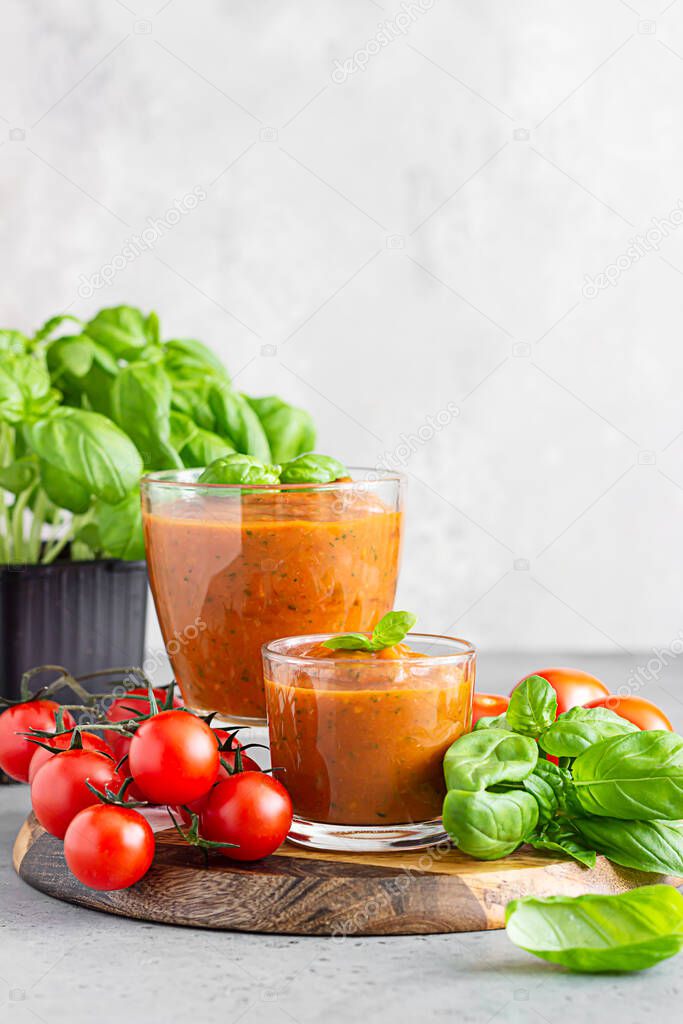 Summer homemade cold tomato cream soup in glass. Traditional Spanish soup gazpacho with basil.