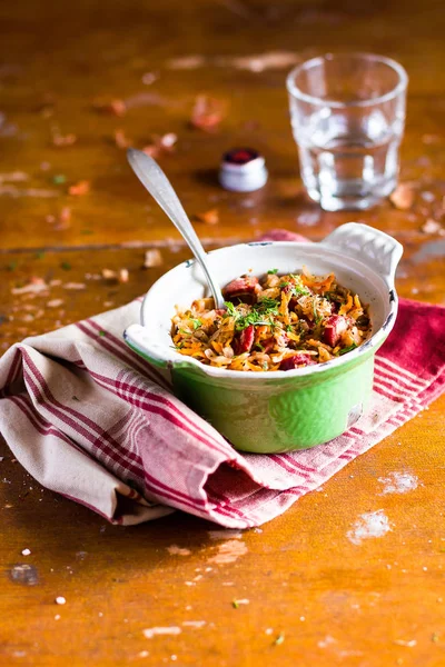 Traditional polish food. Bigos, stewed cabbage with carrot, onion, green lentil and pork meat sausages in a pot on a wooden table, selective focus. German cuisine. Comfort food.