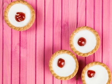 Pembe bir arka plan üzerinde bireysel Bakewell tart