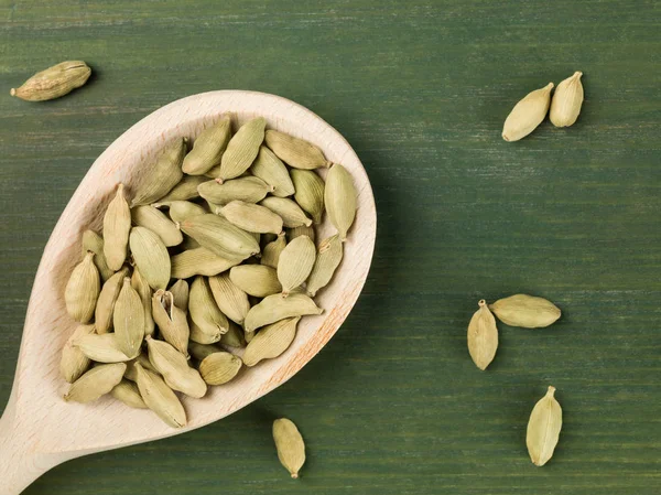 Colher cheia de cápsulas de cardamomo inteiras — Fotografia de Stock