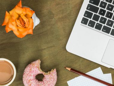 Donut bir bilgisayar iş istasyonu ile bir fincan çay Iced