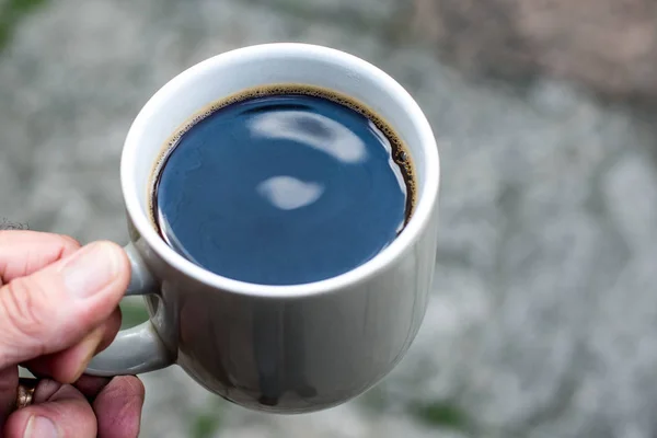 Homem segurando uma caneca de café preto — Fotografia de Stock