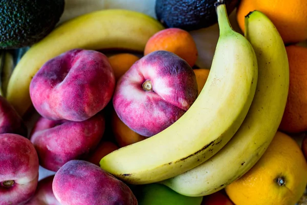 Uma bandeja de frutas frescas, incluindo pêssegos e laranjas de banana — Fotografia de Stock