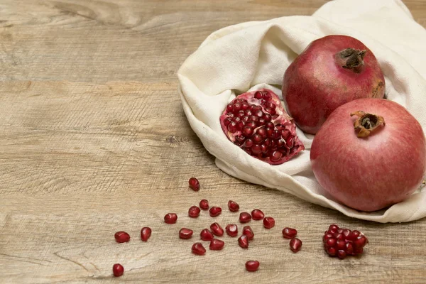 Pomegranates and seeds in the bag. Rustic wooden background.