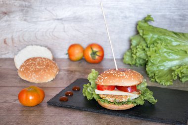 Etli, domatesli, ahşap masadaki peynirli taze lezzetli hamburger..