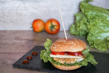 Ev yapımı hamburger, taze et, domates, peynir ve siyah masa..