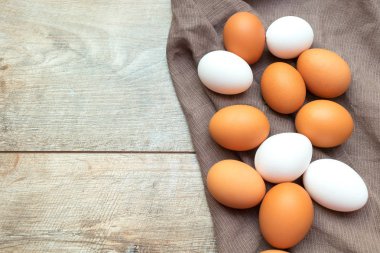 Tahta bir masanın üzerinde tekstil peçetesi olan bir sürü beyaz ve kahverengi yumurta. Kopya alanı olan Paskalya makro arkaplanı.