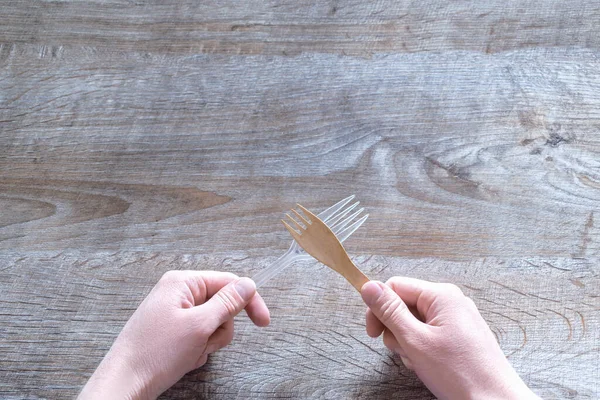 Femme tenant des fourchettes en éco et plastique sur fond en bois avec espace de copie. ustensiles de cuisine vaisselle ustensiles. écologique, écologique, recyclage, concept zéro déchet. vue de dessus . — Photo