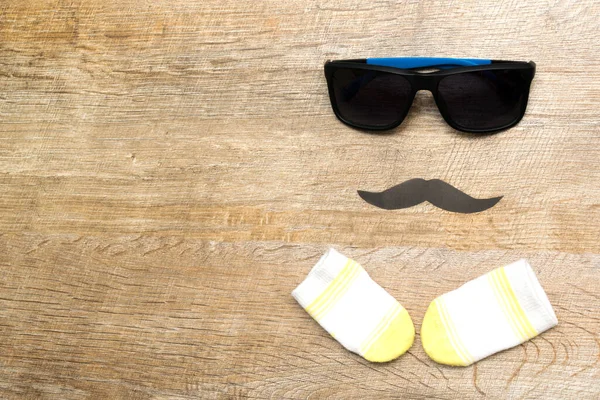 Happy Fathers day holiday concept, sun glasses, socks and mustache on a rustic wooden background with copy space.