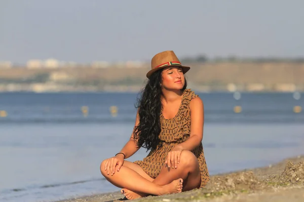 Tanned sexy girl with black hair on the beach sunbathing takes — Stock Photo, Image