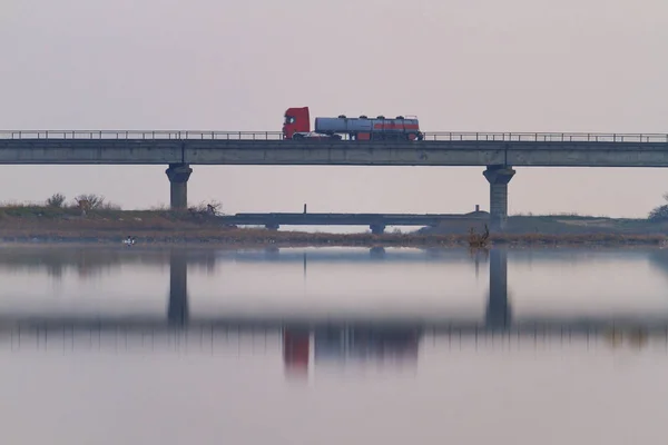 Coche de carga pasa por el puente en la niebla sobre el río — Foto de Stock