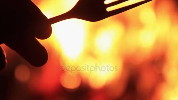 Fork in hand against a background of fire — Stock Video