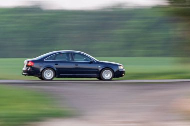 Güzel siyah araba yolda hızlı gidiyor.