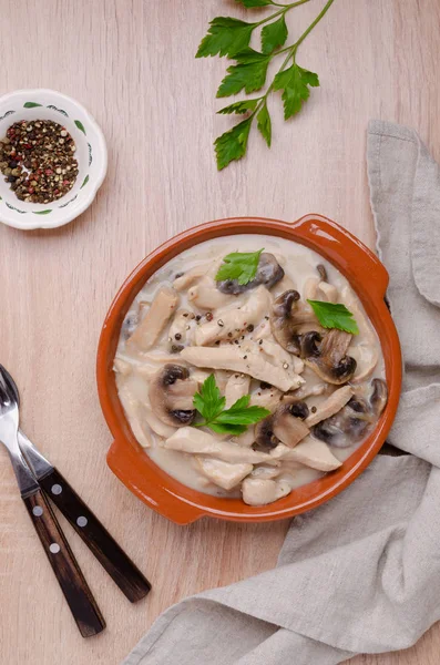 Stewed meat slices with mushrooms in a dish on a wooden background. Selective focus.