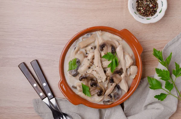 Stewed meat slices with mushrooms in a dish on a wooden background. Selective focus.