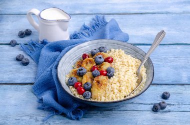 Tahta arka planda meyve ve böğürtlenli buğday lapası. Seçici odak.