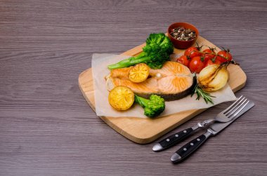 Ahşap arka planda sebze ve baharatlı kızarmış organik somon bifteği. Seçici odak.