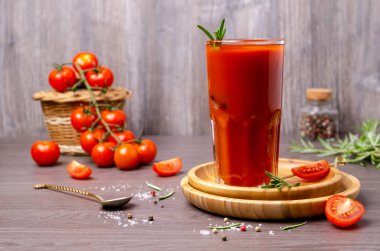 Ahşap arka planda sebze ve baharatla dolu kalın kırmızı bir bardak. Seçici odak.