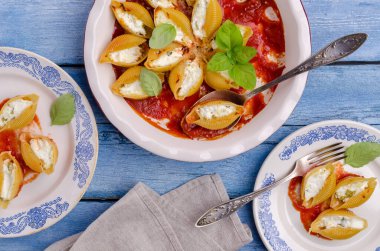 Ricotta ile doldurulmuş makarna ve ahşap zemin üzerinde seramik bir tabakta domates sosunda ıspanak. Seçici odak.