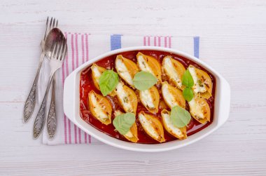 Ricotta ile doldurulmuş makarna ve ahşap zemin üzerinde seramik bir tabakta domates sosunda ıspanak. Seçici odak.