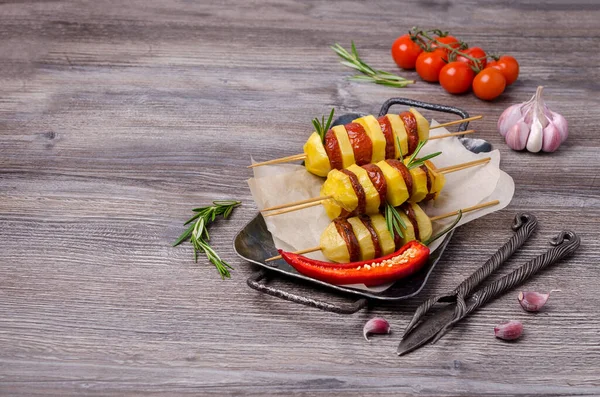 Baked potato slices and sausages on a wooden background. Selective focus.