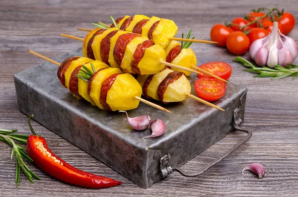 Baked potato slices and sausages on a wooden background. Selective focus.