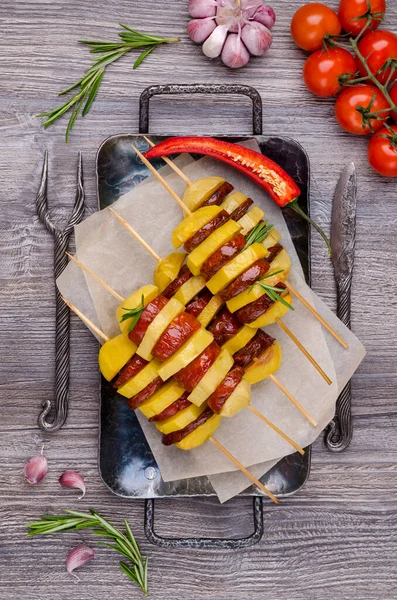 Baked potato slices and sausages on a wooden background. Selective focus.