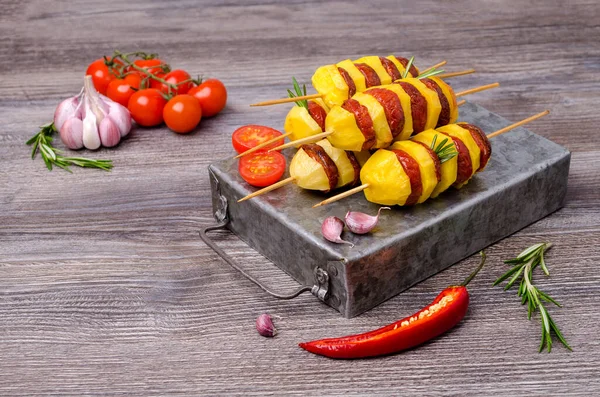 Baked potato slices and sausages on a wooden background. Selective focus.