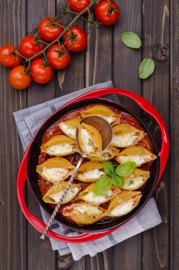 Ricotta ile doldurulmuş makarna ve ahşap zemin üzerinde seramik bir tabakta domates sosunda ıspanak. Seçici odak.