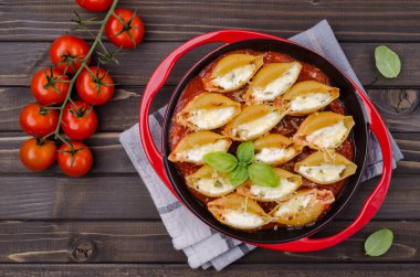 Ricotta ile doldurulmuş makarna ve ahşap zemin üzerinde seramik bir tabakta domates sosunda ıspanak. Seçici odak.