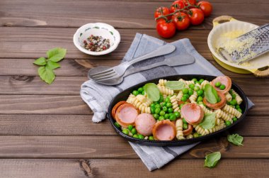 Ahşap arka planda sosis ve sebzeli geleneksel makarna. Seçici odak.