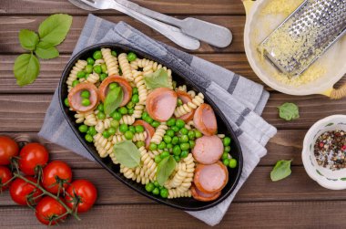 Ahşap arka planda sosis ve sebzeli geleneksel makarna. Seçici odak.