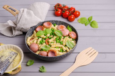 Ahşap arka planda sosis ve sebzeli geleneksel makarna. Seçici odak.